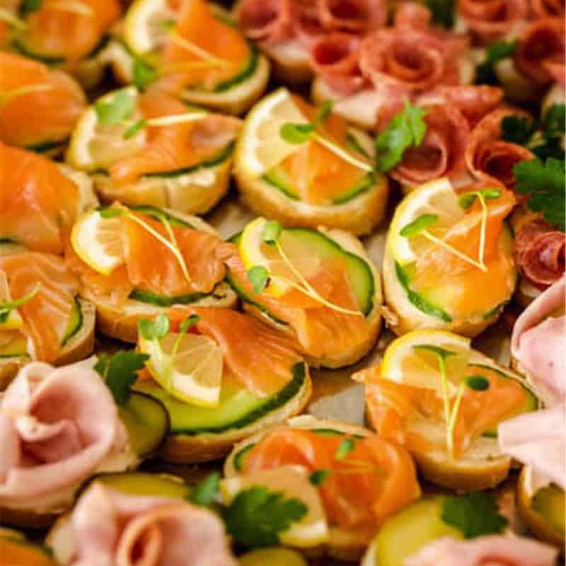 Kanapky s lososem, okurkou a citronem na svatební hostině.