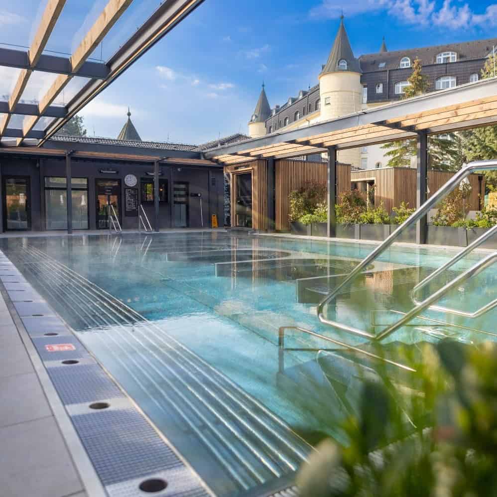 Relaxační bazén v Harmony Javorník s výhledem na zámek, ideální pro odpočinek a wellness. Moderní za.